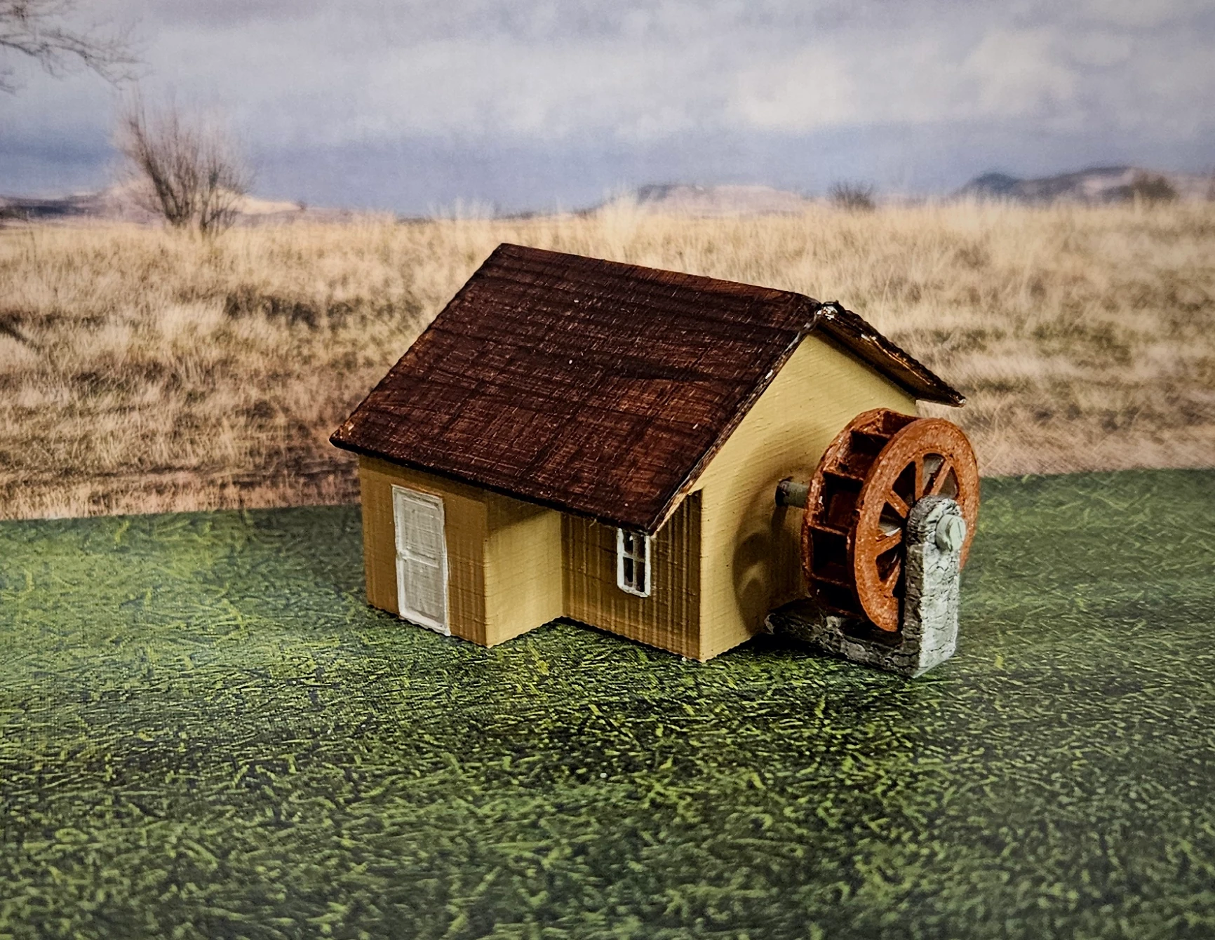 Angled view of N scale waterwheel with large building